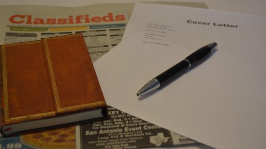 Kartka z napisem list motywacyjny, długopis i gazeta z ogłoszeniami o pracę
