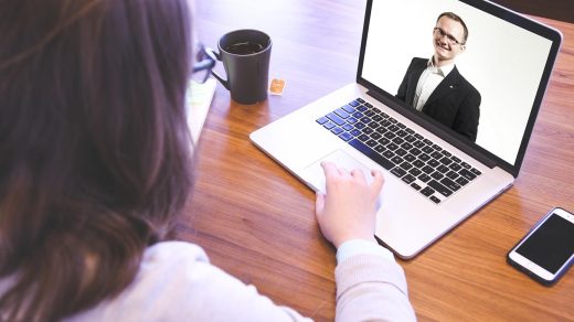 Rozmowa kwalifikacyjna online prowadzona przez laptopa z uśmiechniętym rozmówcą na ekranie