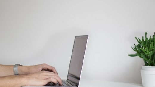 laptop leży na stole, osoba pisze na klawiaturze