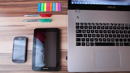 Laptop, telefon komórkowy, kolorowe karteczki i długopisy